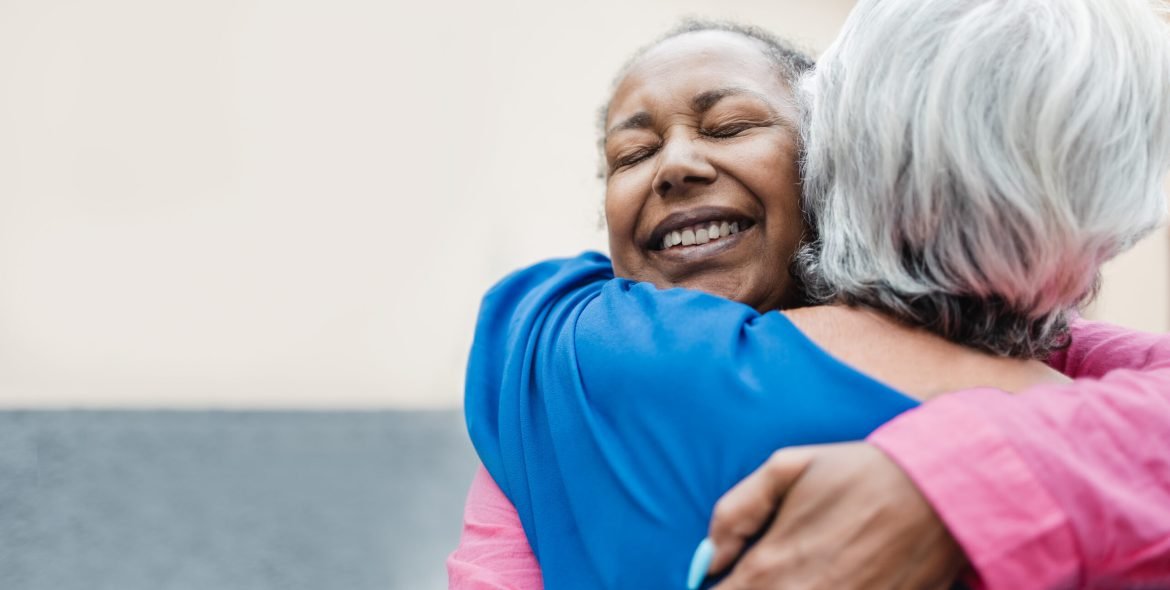 Multiracial senior women hugging each other - Elderly friendship and love concept - Focus on african woman face