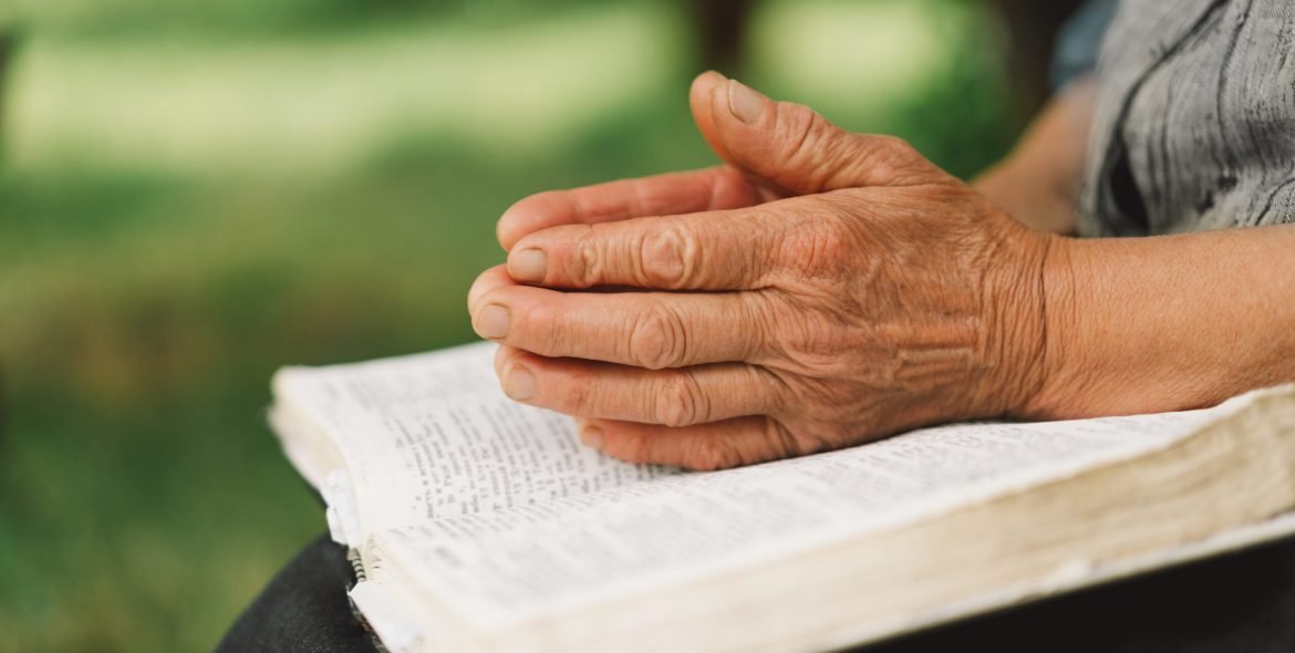 Bible, reading book or old woman praying for hope, help or support in Christianity religion or holy faith. Prayer or senior person studying or worshipping God in spiritual literature at outdoors
