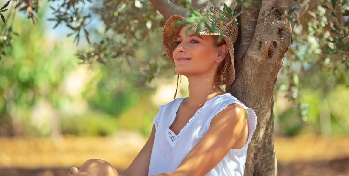 Peaceful woman with pleasure resting in the olive garden, nice farmer girl enjoying freshness of a spring nature, happy life in a countryside