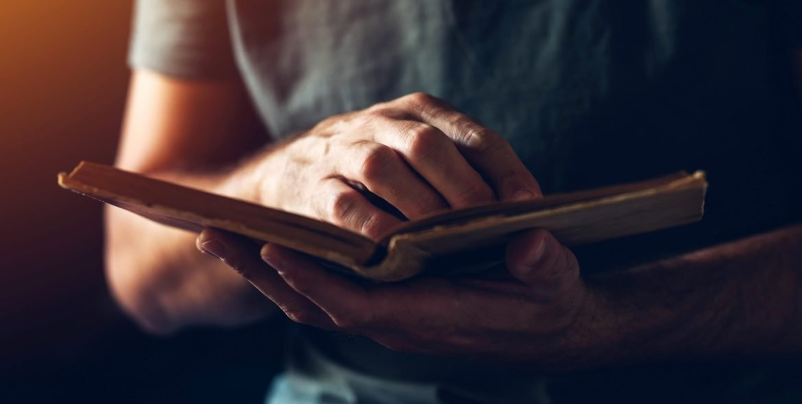 Reading an old book, close up of male hands flipping vintage weathered book pages