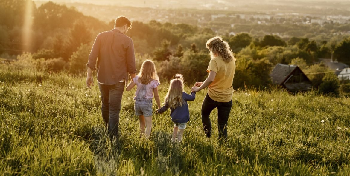 Rear view of family with two daughters walking at the meadow