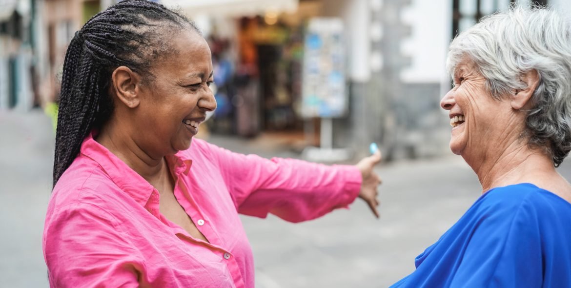 Senior multiracial women meeting and hugging each others outdoor - Focus on african female face