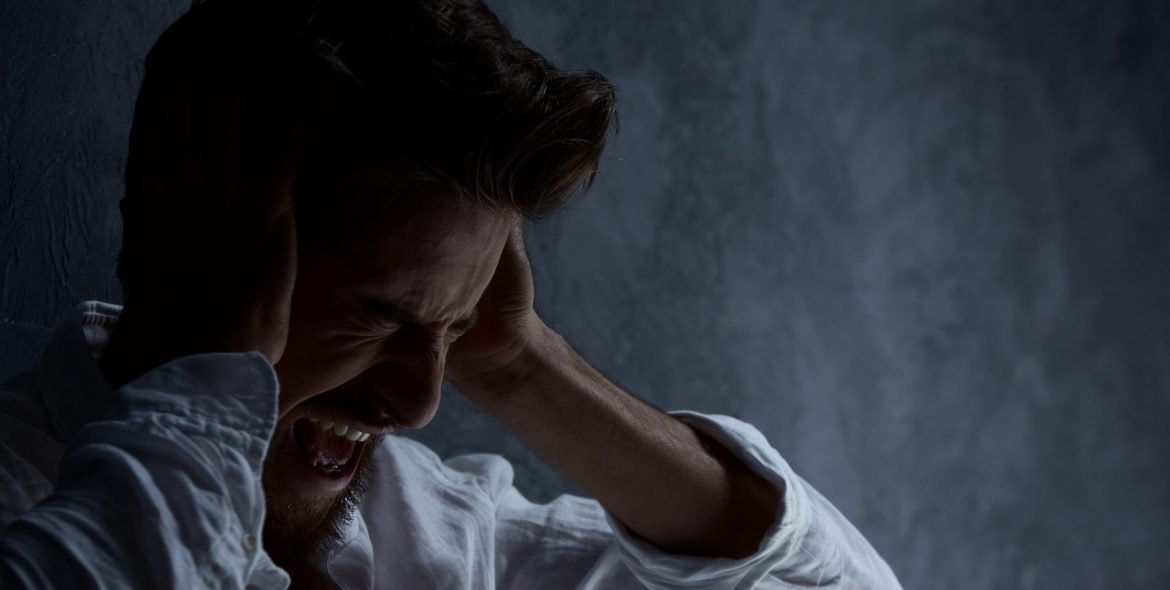 Sick man hearing voices, covering ears and screaming