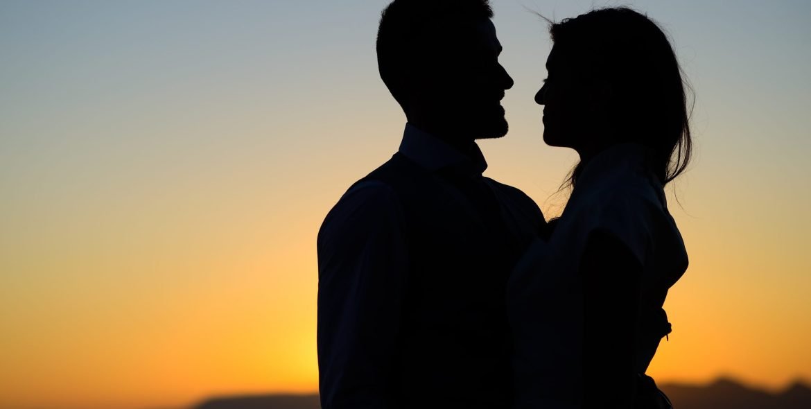 Silhouette of a young bride and groom on Sunset background