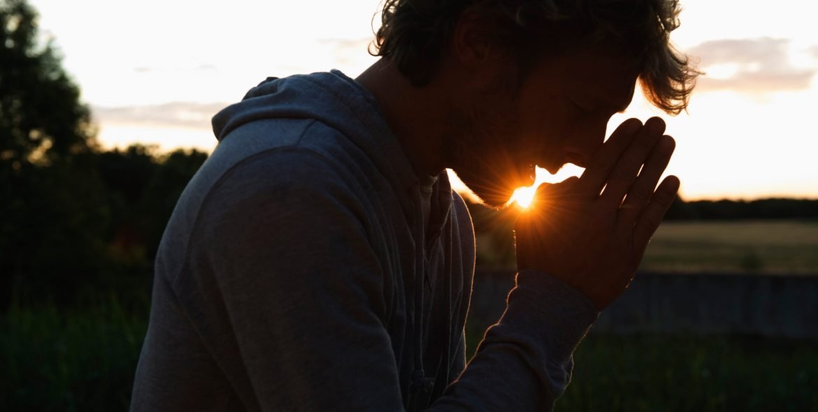 Silhouette of man praying at sunset