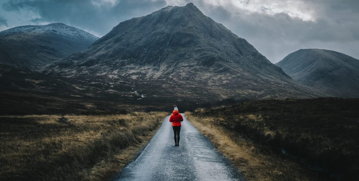 Woman walking on a road in Glen Etive, Scotland