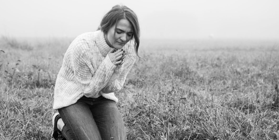 Girl closed her eyes, praying in a field during beautiful fog. Hands folded in prayer concept for faith, spirituality and religion. Peace, hope, dreams concept