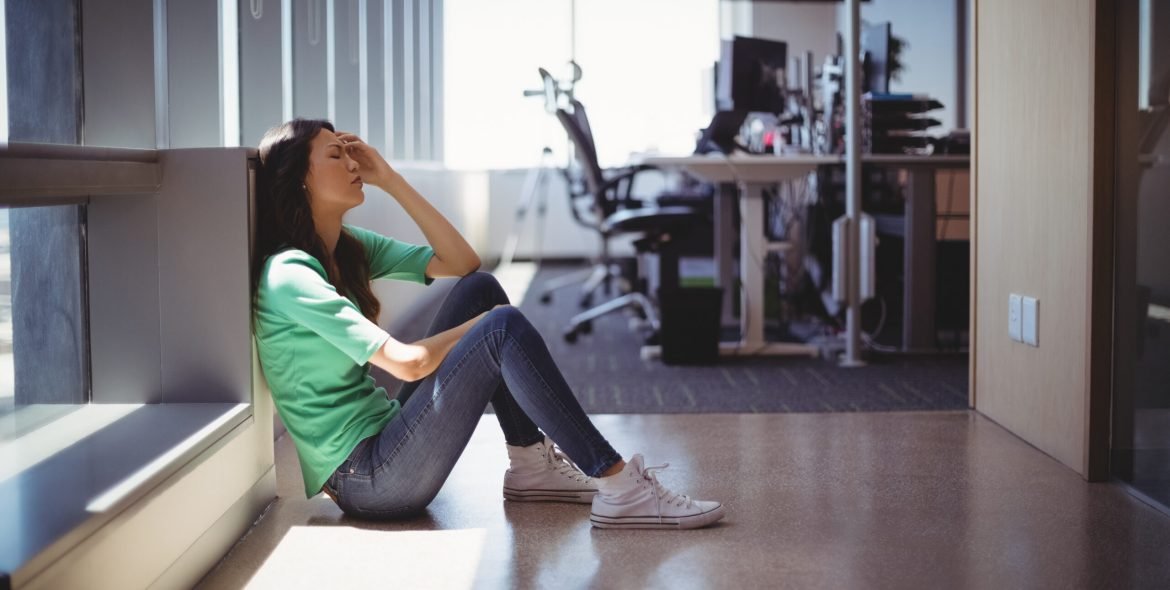 Worried female executive sitting in corridor at office
