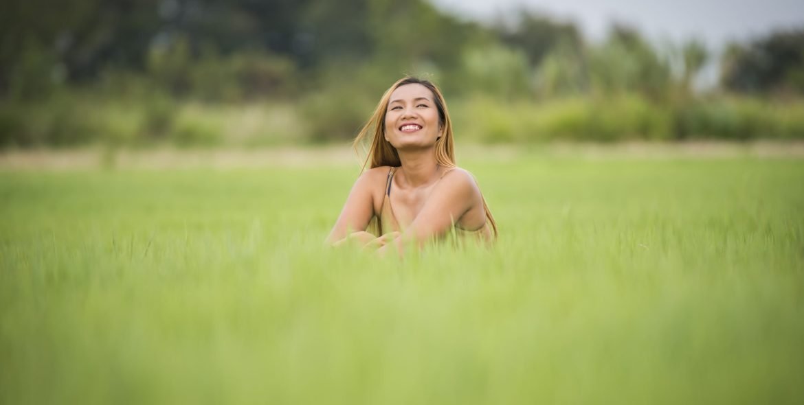 Young woman sitting feel good in grass field.